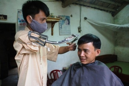 Bị cụt một tay nhưng anh Bùi Đình Dũng vẫn hành nghề cắt tóc.