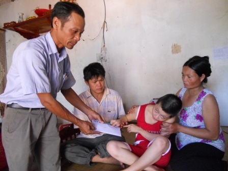 Đại diện chính quyền địa phương trao quà bạn đọc đến gia đình cháu Trang.