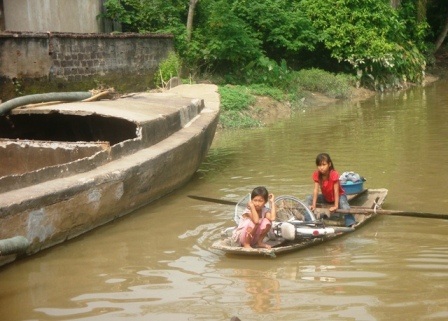 Hai chị em cháu Điền Thị Mai Hương đang chèo đò lên bờ đi nhặt ve chai.