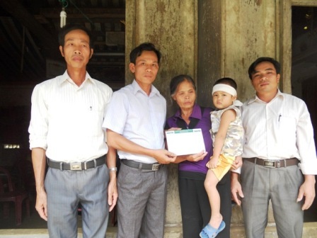 Đại diện chính quyền địa phương trao quà bạn đọc đến hai bà cháu Tuấn Anh.