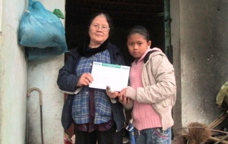 Hai bà cháu Trà My đón nhận món quà của bạn đọc.