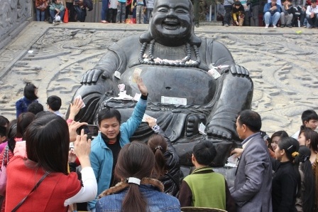 Chen nhau xoa tiền lên tượng Phật Di Lặc cầu may