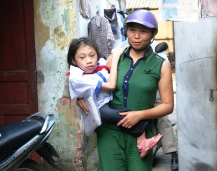 Hàng ngày em Nguyễn Cẩm Vân phải đến trường trên đôi tay của mẹ.