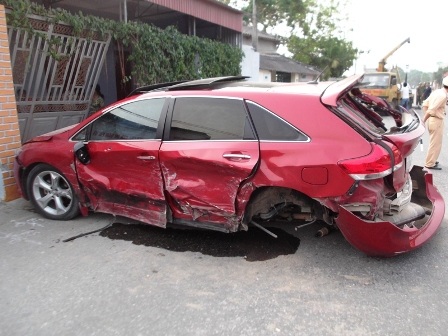 Chiếc xe con màu đỏ bị biến dạng sau cú va chạm.