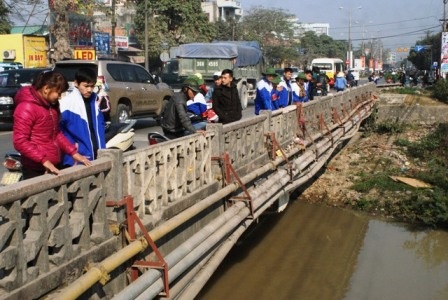  Các bạn đoàn viên đứng trên cầu để đón nhận những túi cá người dân mang đến thả.