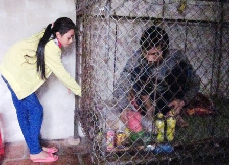  Em Trình Thị Xuân đang đưa nước cho bố mình qua khe của nhỏ vào bên trong chiếc lồng.