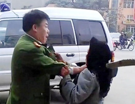 Người mặc sắc phục công an túm cổ áo bà cụ (Hình ảnh được cắt từ clip)