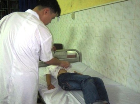 Sau uống sữa “Cô gái Hà Lan” tiếp thị, 12 học sinh nhập viện - 1 Bác sỹ đang thăm khám cho học sinh tại BV Đa khoa tỉnh Nam Định.
