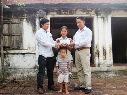 Đại diện chính quyền địa phương trao quà bạn đọc đến hai bà cháu chị Hậu.