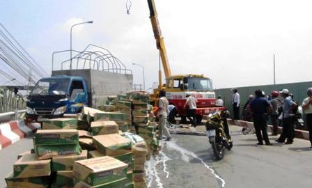 Xe tải lật, hàng trăm thùng sữa tươi rải đầy đường - 1