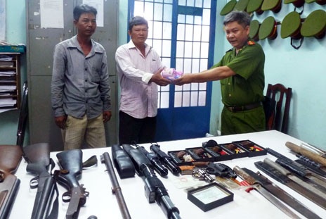 Một người dân giao nộp vũ khí nhận lại quà của công an địa phương.