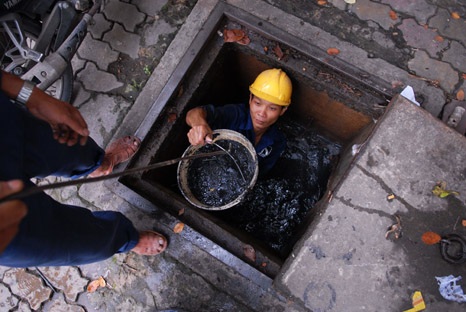 Một công nhân lọt thỏm trong lỗ cống, nơi chẳng ai muốn chui vào