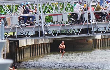Những đứa trẻ vô tư lao xuống sông, đứng trên thành cầu