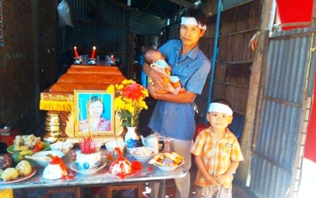 Anh Tuấn bồng đứa con gái 2 tháng tuổi và người con nhỏ đứng
cạnh quan tài vợ ở Vĩnh Long