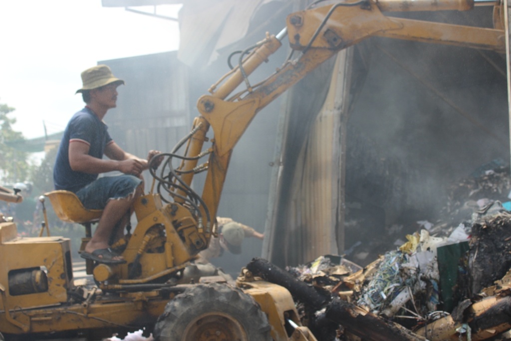 Xe cuốc đào bới đống phế liệu