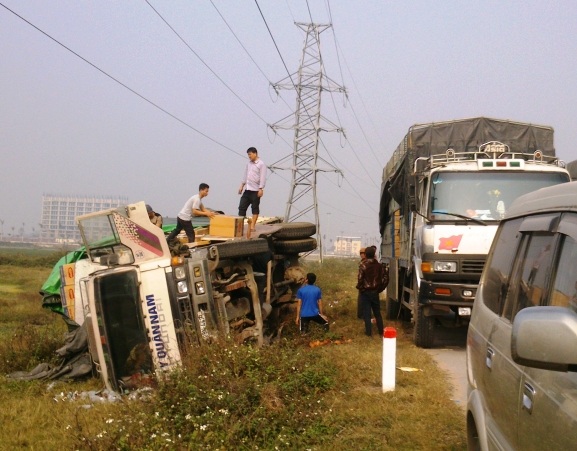 Chiếc xe chở hàng mất lái lật nhào ven quốc lộ đang được xe khác đến ứng cứu