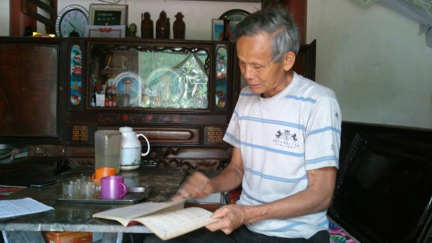 Ông Hán buồn bã giở cuốn sổ ghi chép những người trong làng mất vì căn bệnh ung thư