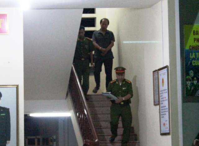 Một cán bộ kiểm lâm bị còng tay dẫn giải đi