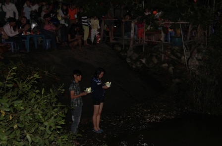 Hai bạn trẻ nguyện cầu và thả đèn hoa đăng xuống sông Rạch Chiếc