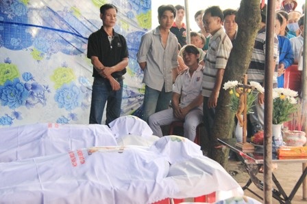Anh Luân (ngồi) đau đớn nhìn thi thể của những người thân