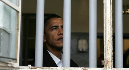 Obama nhìn qua cửa sổ nơi từng giam giữ Mandela. Ảnh: AP