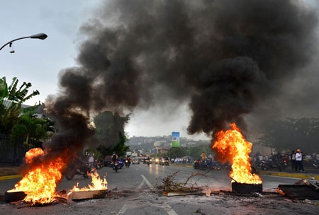 Thủ đô Venezuela tê liệt sau vụ thủ lĩnh đối lập bị bắt - 1 Người biểu tình đối lập đốt lốp xe, cản trở đại lộ chính ở thủ đô Caracas trong ngày 18/2. Ảnh: AP