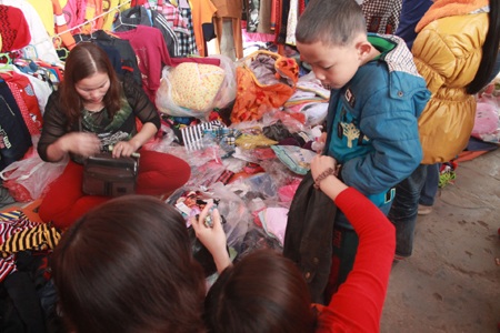 Một cậu bé được mẹ đưa đi chợ sắm quần áo mới.