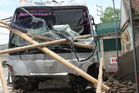 Xe khách lao vào nhà dân, hàng chục người hoảng loạn - 1 Chiếc xe khách hư hỏng nặng phần đầu sau khi đâm sập tường nhà dân.