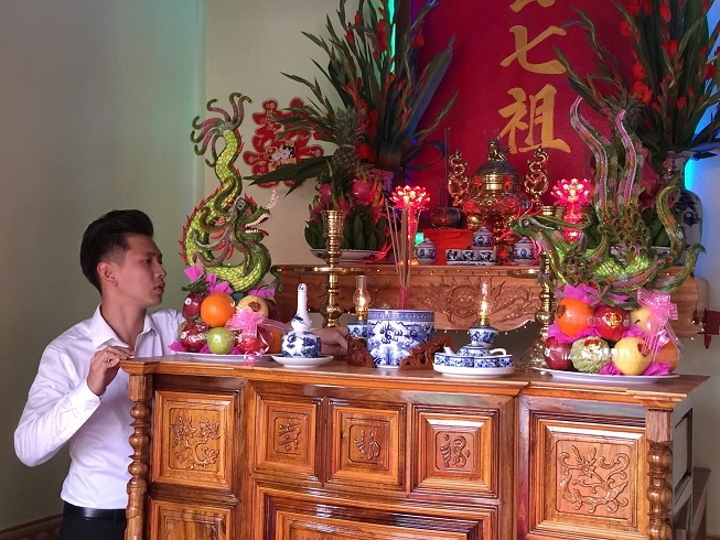 Chú rể Đỗ Khải An phụ giúp chỉnh trang lại bàn thờ tổ tiên trước khi bắt đầu buổi lễ.