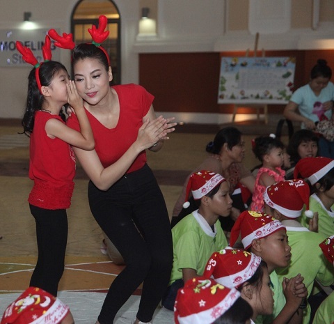 Cô bé liên tục nói nhỏ với mẹ trong suốt buổi trao quà Giáng sinh cho các trẻ mồ côi.