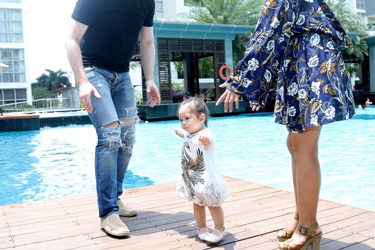 Vợ chồng nữ ca sĩ Socola cùng ở cạnh bên bé Sol trong lúc cô bé tập đi bên hồ bơi.