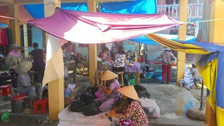 Chợ mới làm nửa tháng nhưng đã hư hỏng, không che nổi nắng mưa - 1 Ngồi trong chợ mà phải lấy bạt che tạm bợ vì toàn bộ nắng, mưa đều hắt trực tiếp vào người dân