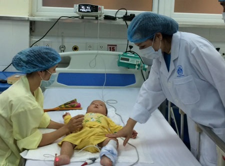 Bộ trưởng Bộ Y tế thăm hỏi bệnh nhi. Bà ân cần động viên người mẹ, dặn dò người mẹ cố gắng,