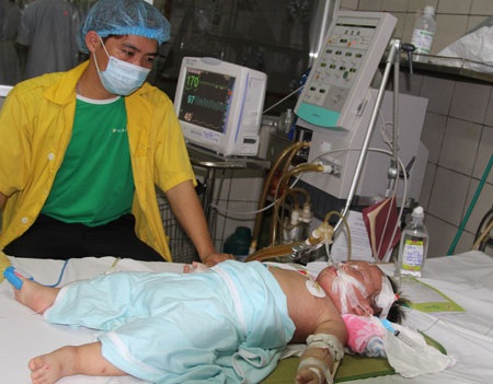 Bộ trưởng Bộ Y tế thăm hỏi bệnh nhi. Bà ân cần động viên người mẹ, dặn dò người mẹ cố gắng,