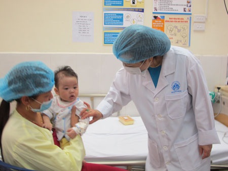 Bộ trưởng Bộ Y tế thăm hỏi bệnh nhi. Bà ân cần động viên người mẹ, dặn dò người mẹ cố gắng,