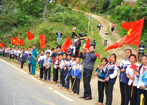 Học sinh ở thị trấn Mường Ảng vẫy chào đoàn đua.