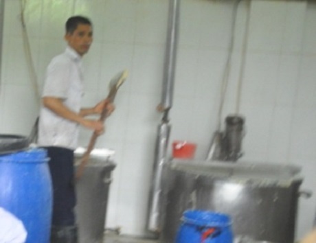 Dùng gậy gỗ khuấy vào thùng sữa