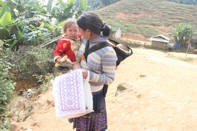Phụ nữ H'Mông tranh thủ lúc địu con cũng mang đồ ra thêu