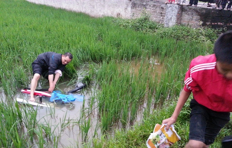 Người dân giải cứu chiếc xe máy nằm dưới ruộng sau khi xe con húc văng xuống.