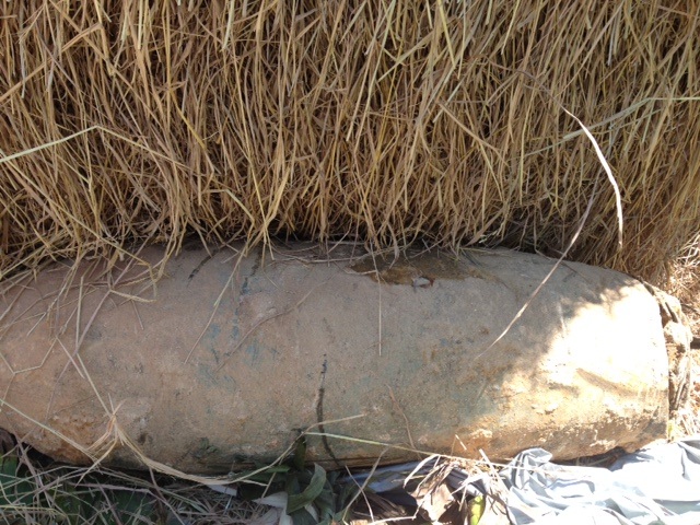 Quả bom sau khi phát hiện được người dân đưa lên khỏi mặt đất để trong một đống rơm.