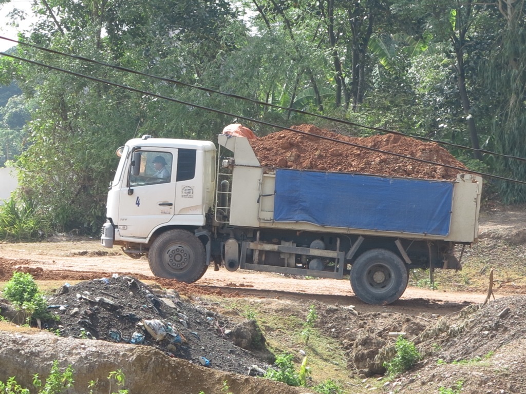 Xe chở đất có bạt nhưng không che cứ để mặc đất rơi vãi dọc đường.
