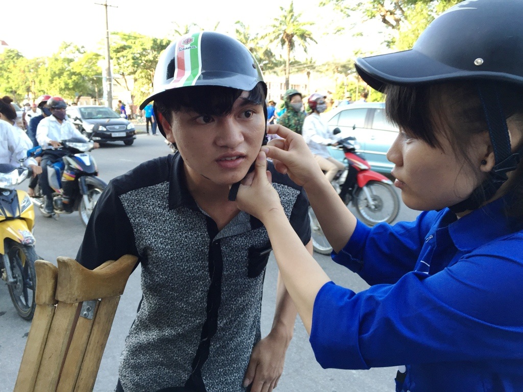 Sinh viên tình nguyện giúp đỡ Tuấn cài quai mũ bảo hiểm để về phòng trọ.