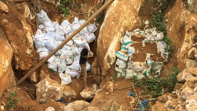 Lao động bốc những bao tải đất lẫn quặng chui từ hầm trong núi lên khỏi mặt đất.