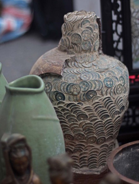 Chum tiền bằng đất nung bị vỡ lộ ra hàng nghìn đồng tiền xếp chồng lên nhau.