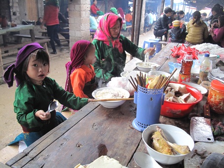 Đi chợ mua đồ đã xong, lũ trẻ nhỏ được mẹ cho ăn phở nóng – món ăn của người miền xuôi đem đến bán.