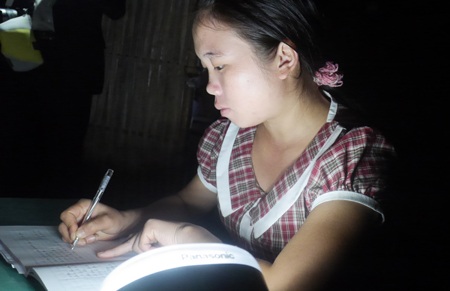 Nữ giáo viên soạn giáo án dưới ánh đèn năng lượng mặt trời.