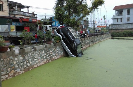 Ô tô nổ máy trong nhà, bất ngờ lao vọt... xuống ao - 1 Chiếc xe lao từ trong nhà ra cắm thẳng xuống ao.