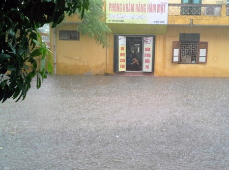 Nước mưa mấp mé cửa dù nhà đã đôn cao cả mét so với mặt đường (ảnh bạn đọc Kiều Thu cung cấp).