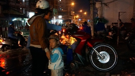 Một gia đình vất vả đẩy chiếc xe chết máy vì ngập nước lên vỉa hè tìm chỗ trú