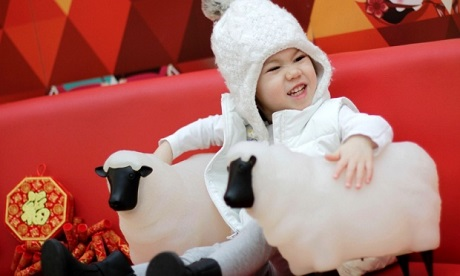 Những con số ấn tượng về Tết âm lịch 2015 ở Trung Quốc - 1 Một em bé bên cạnh 2 chiếc đèn hình cừu tại một trung tâm mua sắm ở Vancouver, Canada. (Ảnh: